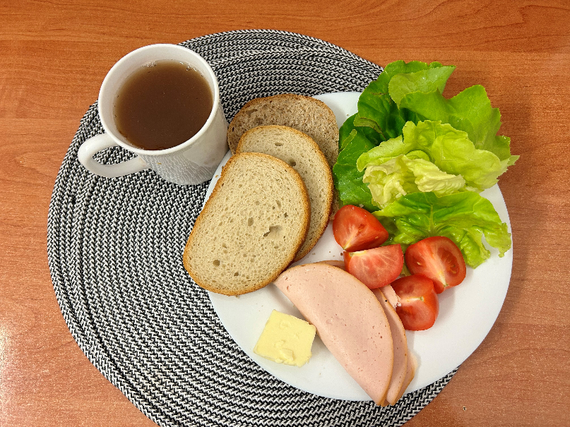Na zdjęciu: Herbata czarna ekspresowa z cytryną Cateringowa, Chleb mieszany pszenno-żytni, Chleb Graham, Masło extra 82%, Filet zapiekany drobiowy, Pomidor, Sałata zielona